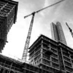 grayscale photo of crane in front of building